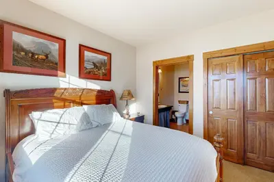 a bedroom with a white bed and a wooden door at Horse Lodges 5-102 in Granby