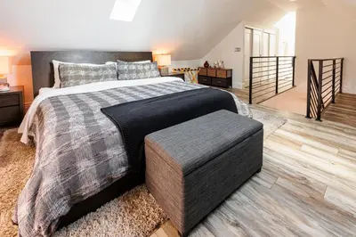 a bedroom with a large bed with a ottoman at Lux Newly Remodeled DT, Patio, Fully Stocked 5Bd, 3Ba in Denver
