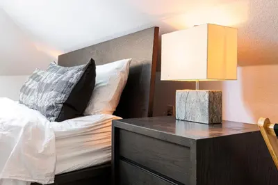 a bedroom with a bed and a table with a lamp at Lux Newly Remodeled DT, Patio, Fully Stocked 5Bd, 3Ba in Denver