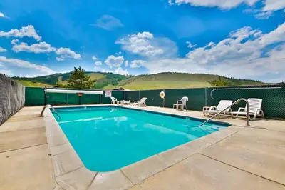 a swimming pool on a patio with chairs around it at Mountainside 001 in Granby