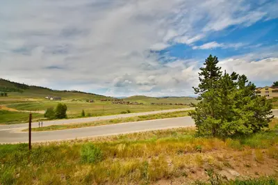 a road in the middle of a field with a tree at Mountainside 001 in Granby