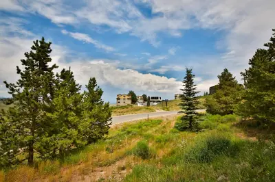 a road in the middle of a field with trees at Mountainside 001 in Granby
