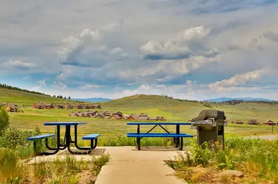 two picnic tables and a trash can in a field at Mountainside 037 in Granby