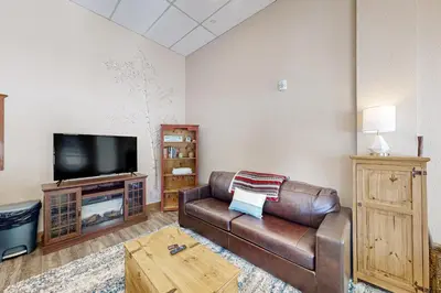 a living room with a leather couch and a flat screen tv at Lakefront Keystone Studio in Keystone