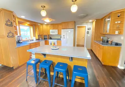 a kitchen with a large island with four blue stools at Stylish two homes in one house 6 bedrooms 2 kitchens in Longmont