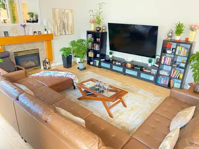a living room with a brown leather couch and a flat screen tv at Bright, big home walking distance to Mcintosh lake in Longmont