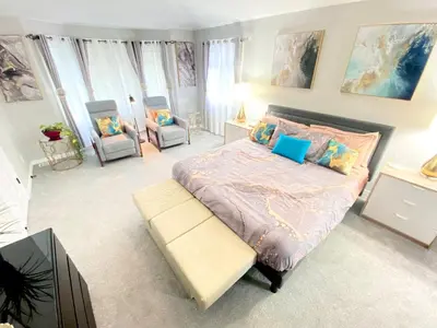 a bedroom with a large bed and two chairs at Bright, big home walking distance to Mcintosh lake in Longmont