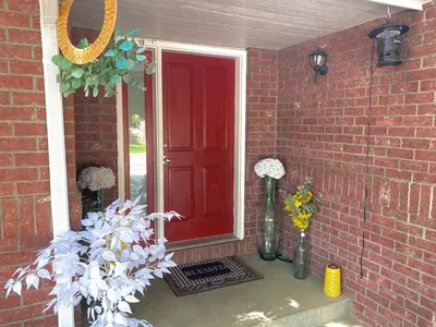 a red door on a brick house with vases of flowers at Bright, big home walking distance to Mcintosh lake in Longmont