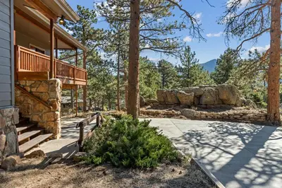 a house with a porch and a stone wall at 1k Pine Knolls - Estes in Estes Park