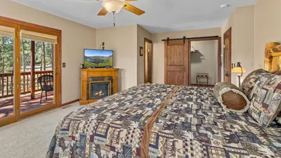 a bedroom with a bed and a tv and a balcony at 1k Pine Knolls - Estes in Estes Park