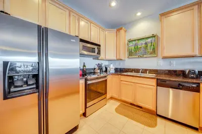 a kitchen with wooden cabinets and a stainless steel refrigerator at 6 Mi to Keystone Resort Dillon Condo with Balcony in Dillon