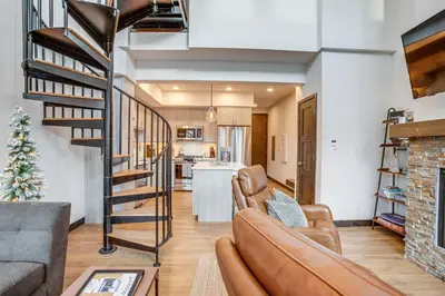 a living room with a couch and a spiral staircase at Walk to Cooper Creek Square Condo with Hot Tub! in Winter Park