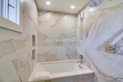 a bathroom with a white tub and marble walls at Mtn Escape with Hot Tub, By Trails in Grand Lake! in Grand Lake
