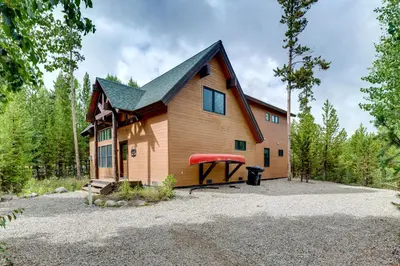 a large house with a red boat in front of it at Mtn Escape with Hot Tub, By Trails in Grand Lake! in Grand Lake