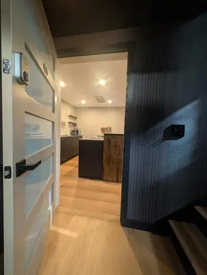 a hallway with a door and a kitchen in the background at Cliff's Edge Brewing BBnB in Denver