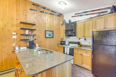 a kitchen with wooden cabinets and a stainless steel refrigerator at Pool and Hot Tub Access Condo in Winter Park! in Winter Park