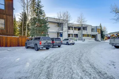 a parking lot with cars parked in front of a building at Steps to River Run Gondola Ski Condo with Views! in Keystone