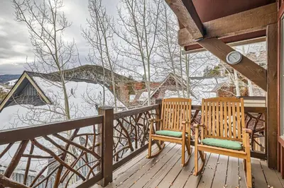 two chairs sitting on a porch with a view of the snow at 6 Cabin in the Pines home in Keystone