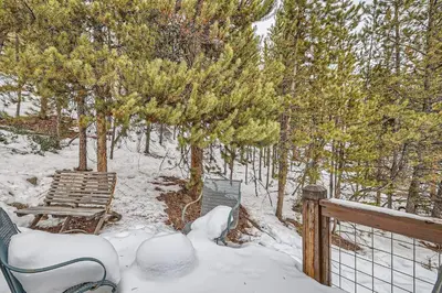 a snow covered deck with a bench and trees at 6 Cabin in the Pines home in Keystone