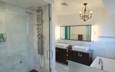 a bathroom with a shower and two sinks and a mirror at Denver Lower Highlands Modern Home in Denver