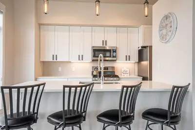 a kitchen with a counter with four chairs in it at Cozy Downtown Condo with Jacuzzi 5 Min to Resort in Winter Park