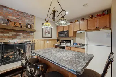 a kitchen with a refrigerator and a table with chairs at Hi Country Haus 11-12 in Winter Park