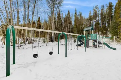 a playground in the snow with a swing at Hi Country Haus 11-12 in Winter Park