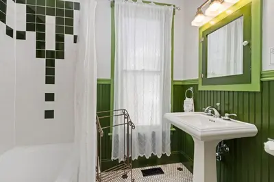 a green and white bathroom with a sink and a shower at City Park Charm - Vintage Home with Modern Comforts in Fort Collins