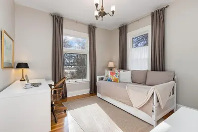 a bedroom with a bed and a desk and windows at City Park Charm - Vintage Home with Modern Comforts in Fort Collins