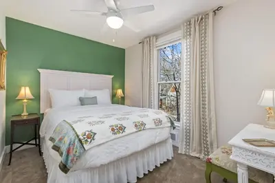 a bedroom with a white bed and a green wall at City Park Charm - Vintage Home with Modern Comforts in Fort Collins