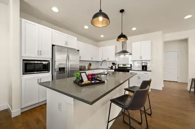 a kitchen with white cabinets and a large island with chairs at The Colorado House in Old Town Brewery District in Fort Collins
