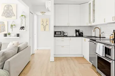 a white kitchen with white cabinets and a couch at Bright & Modern - King Suite - Creekside Trail in Boulder