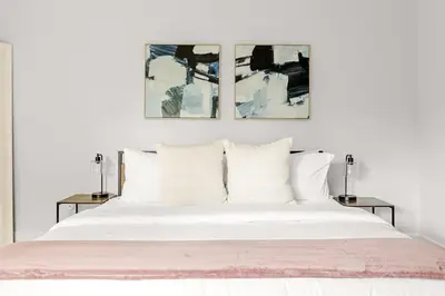 a bedroom with a white bed with three paintings on the wall at Bright & Modern - King Suite - Creekside Trail in Boulder