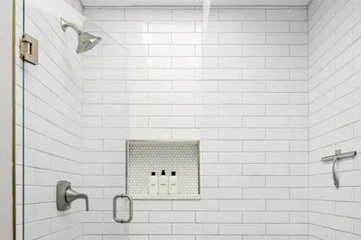a bathroom with a white tiled shower with three bottles at Bright & Modern - King Suite - Creekside Trail in Boulder