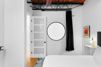 a white bedroom with a mirror on the wall at Suite No 1 & No 2 in Denver