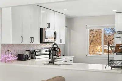 a kitchen with white cabinets and a sink at Modern Family Friendly Escape Central 5 Bedroom in Denver