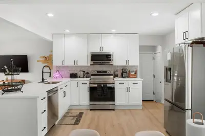 a kitchen with white cabinets and stainless steel appliances at Modern Family Friendly Escape Central 5 Bedroom in Denver