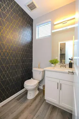a bathroom with a toilet and a sink and a mirror at Spacious 4BD Near Denver w BBQ, Game Room & Office in Commerce City