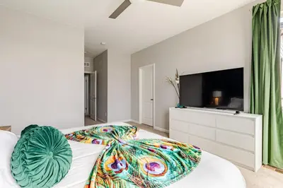 a bedroom with a large bed and a flat screen tv at Spacious 4BD Near Denver w BBQ, Game Room & Office in Commerce City