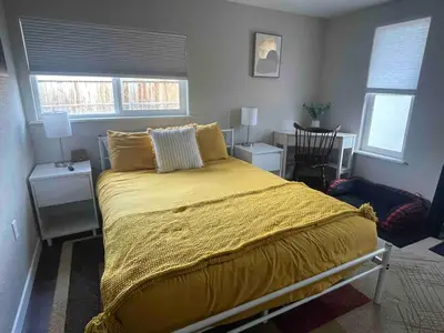 a bedroom with a bed with yellow sheets and windows at 4BR Longmont Escape with Cold Plunge & Sauna - Pets OK! in Longmont