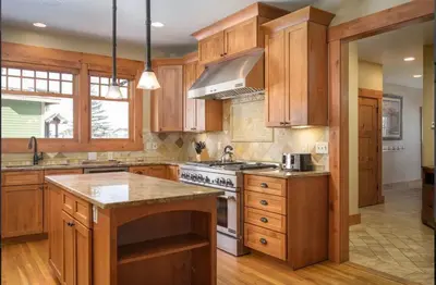 a kitchen with wooden cabinets and a stove top oven at Luxe Winter Park Escape - 5BR with Hot Tub & Game Room in Winter Park
