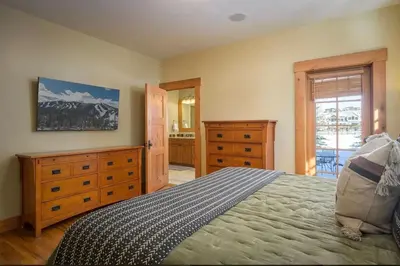 a bedroom with a bed and dressers and a bathroom at Luxe Winter Park Escape - 5BR with Hot Tub & Game Room in Winter Park