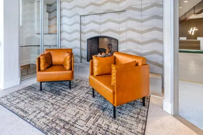 two orange chairs in a lobby with a fireplace at Holiday Inn Frisco by IHG in Frisco