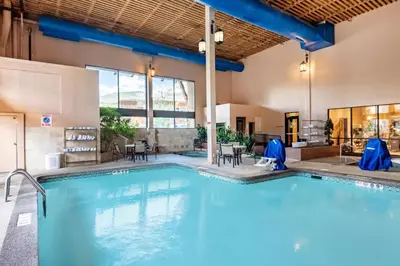 a swimming pool with blue chairs and tables in a building at Holiday Inn Frisco by IHG in Frisco