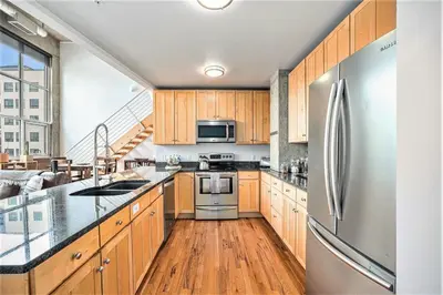 a kitchen with wooden cabinets and a stainless steel refrigerator at Stylish City Loft Walk to Dining & Shops in Denver