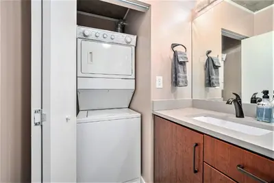 a bathroom with a washer and dryer next to a sink at Stylish City Loft Walk to Dining & Shops in Denver