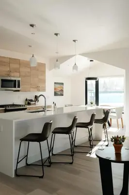 a kitchen with a large white counter and chairs at Chic Silverthorne Condo with Rocky MTN Vista Views in Silverthorne