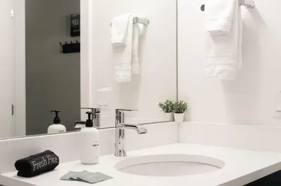 a white bathroom with a sink and a mirror at Riverfront Patio - Hot Tub - Luxe Silverthorne in Silverthorne