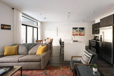 a living room with a couch and a kitchen at Riverfront Patio - Hot Tub - Luxe Silverthorne in Silverthorne