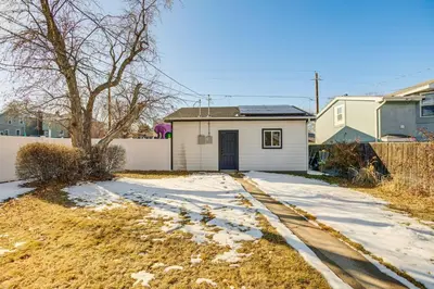 a house with snow on the ground next to a driveway at Walk to City Park Chic Home with Hot Tub and Yard in Denver